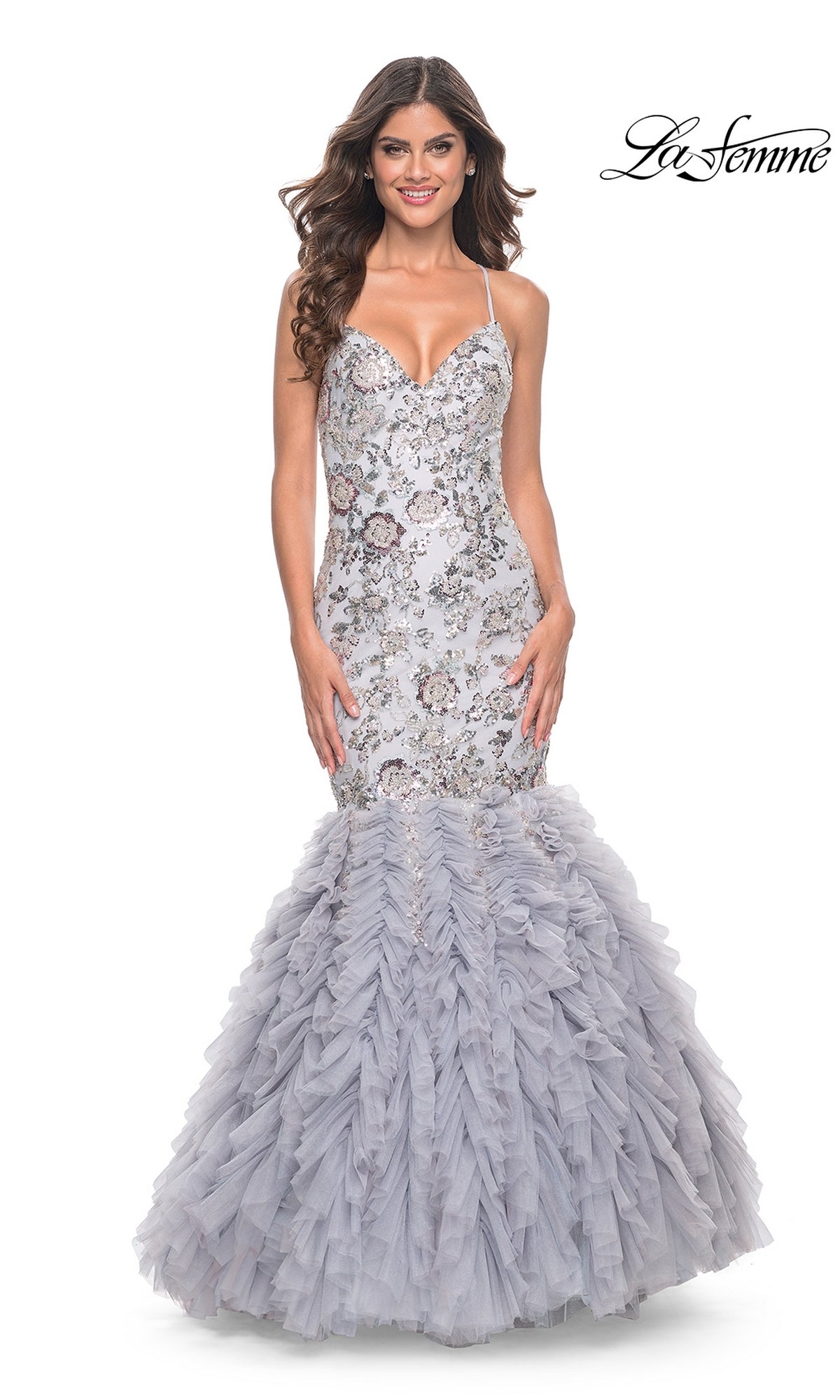 A woman smiles in the La Femme Silver Ruffled Long Prom Dress 32105, featuring floral embroidery and a tulle skirt. The La Femme logo is displayed in the top right corner.